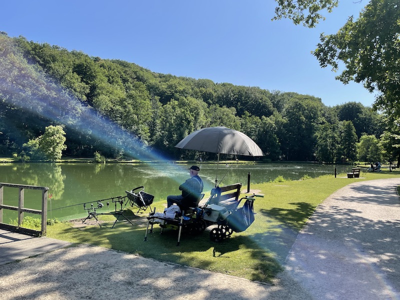 Photo d'un pratiquant de la pêche autour du lac sous son parasol