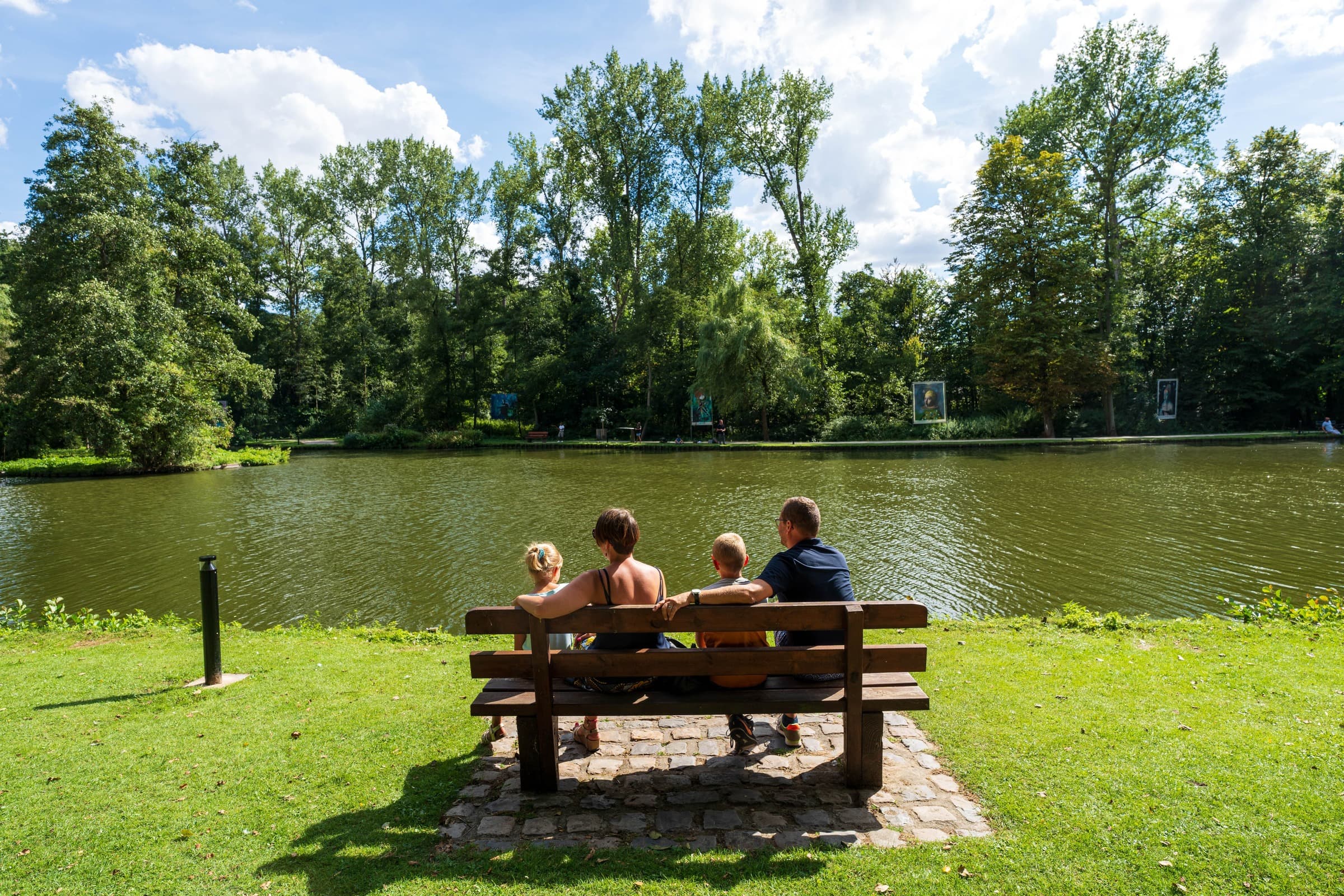 Photo d'une famille et de leurs 2 enfants assis sur un banc autour du lac du bois des rêves