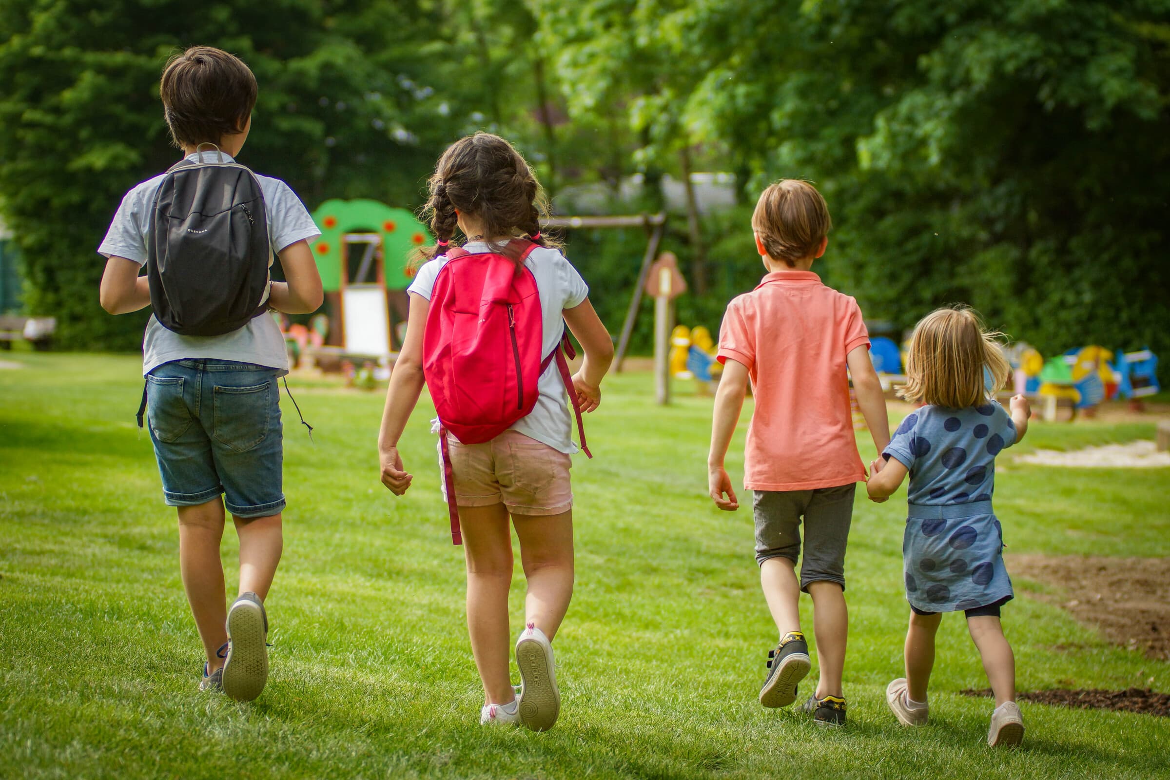 Photo de dos de 4 enfants dans la plaine de jeux des bois des rêves