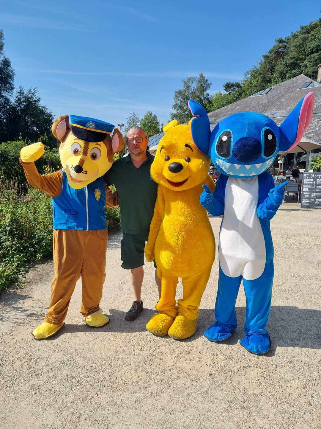 Photo d'un membre de l'équipe des Bois des Rêves avec les personnages déguisés de Winnie l'Ourson, Stitch et Pat' Patrouille