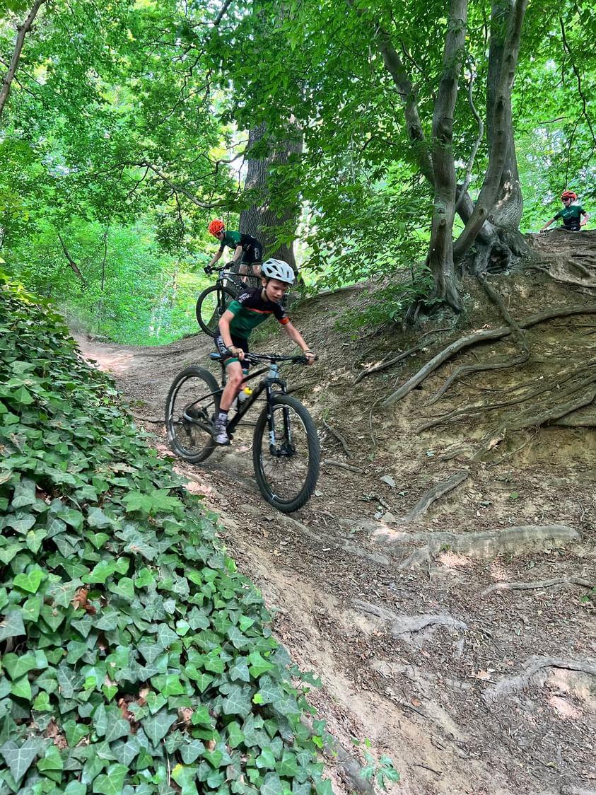 Photo d'un enfant habillé en vert faisant une descente sur son VTT dans le Domaine des Bois des Rêves