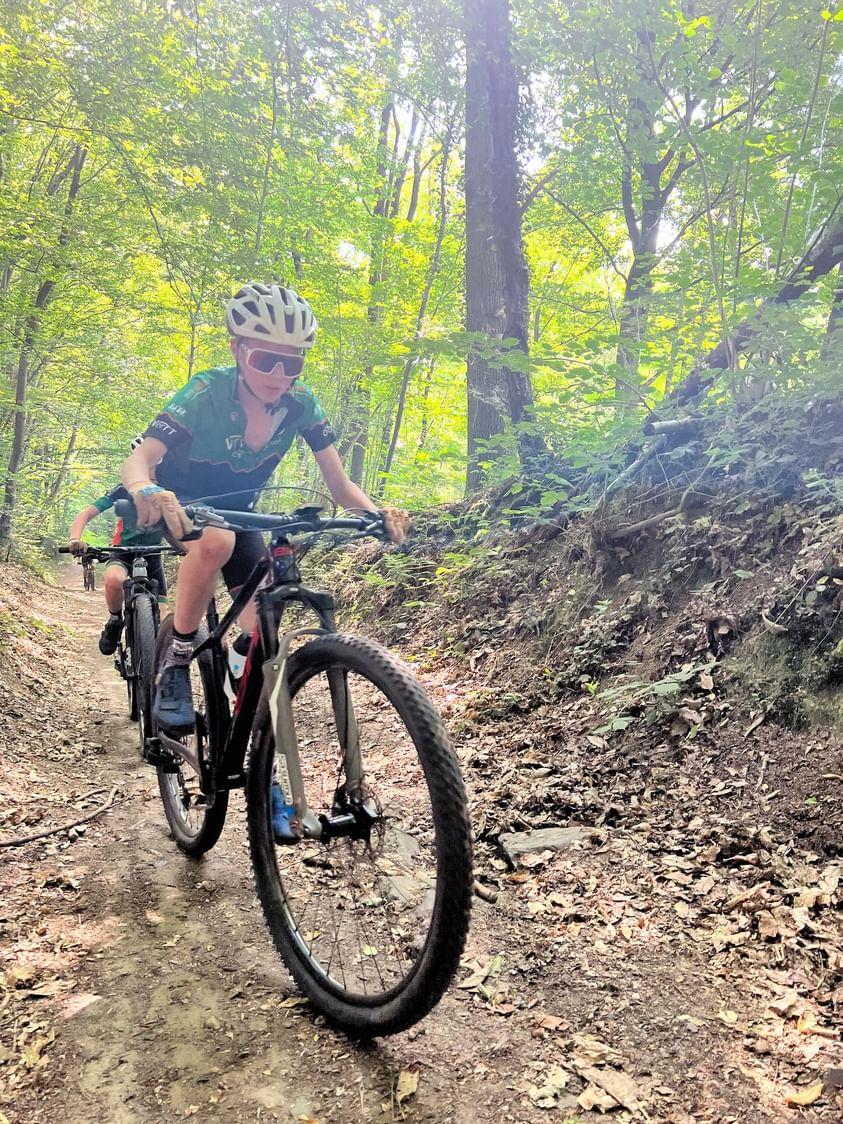 Photo d'un enfant habillé en vert pédalant sur son VTT dans le Domaine des Bois des Rêves